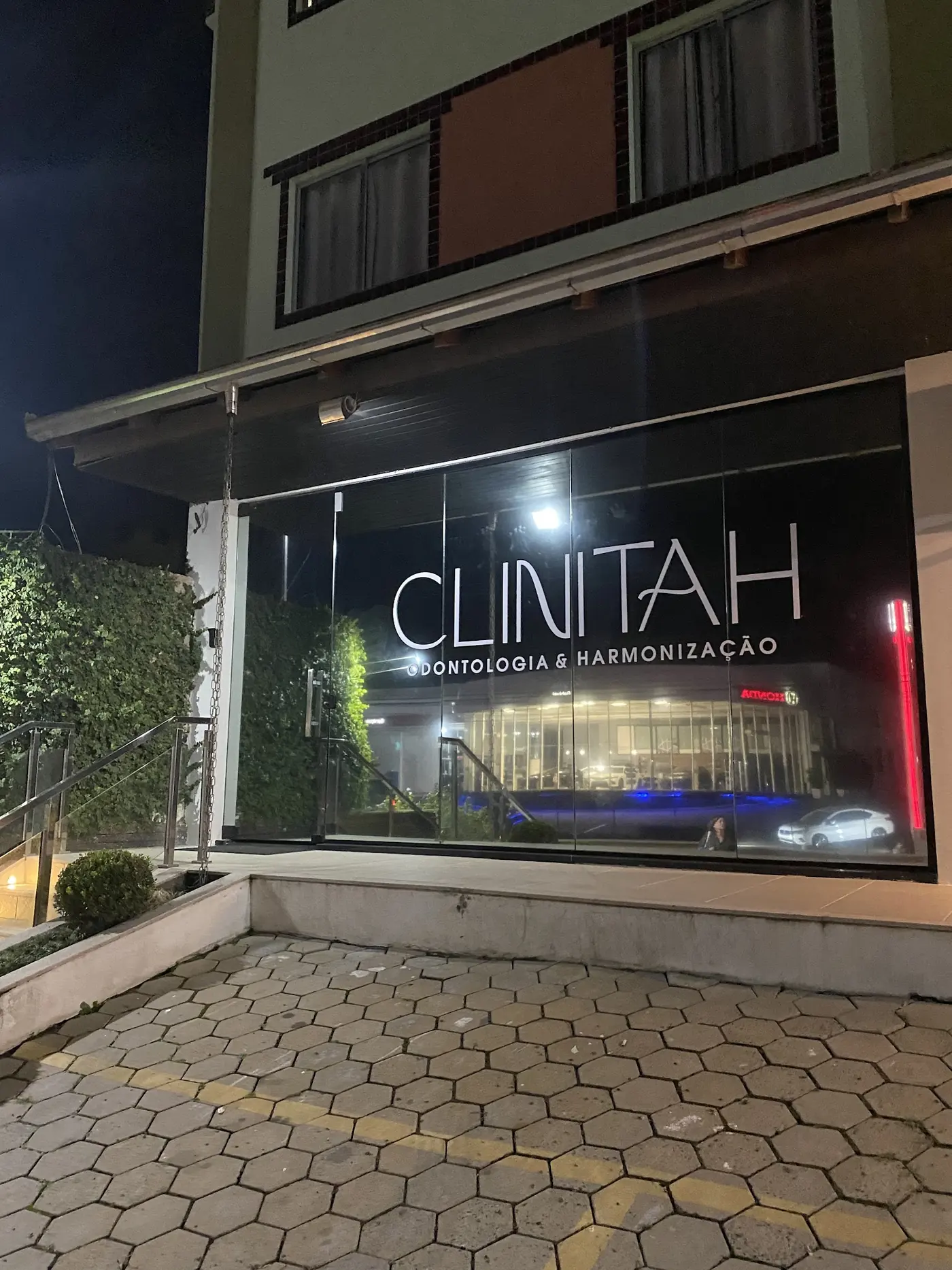 Fachada da Clinitah à noite, com o nome no vidro